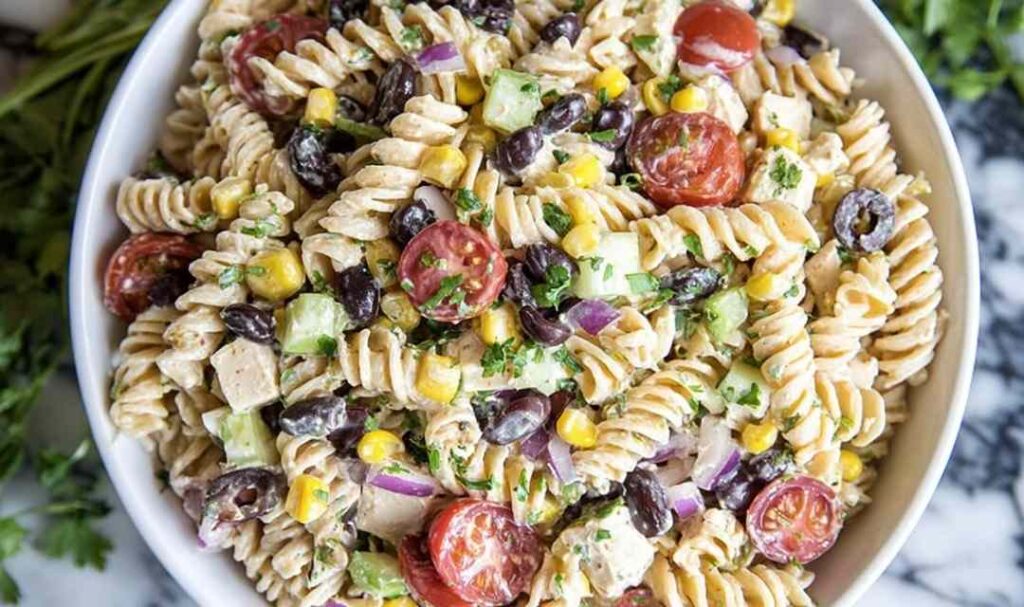 Southwest pasta salad with chipotle ranch dressing, grilled chicken, black beans, and corn in a large bowl