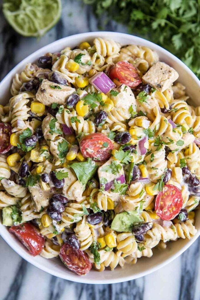 Southwest pasta salad with chipotle ranch dressing, grilled chicken, black beans, and corn in a large bowl