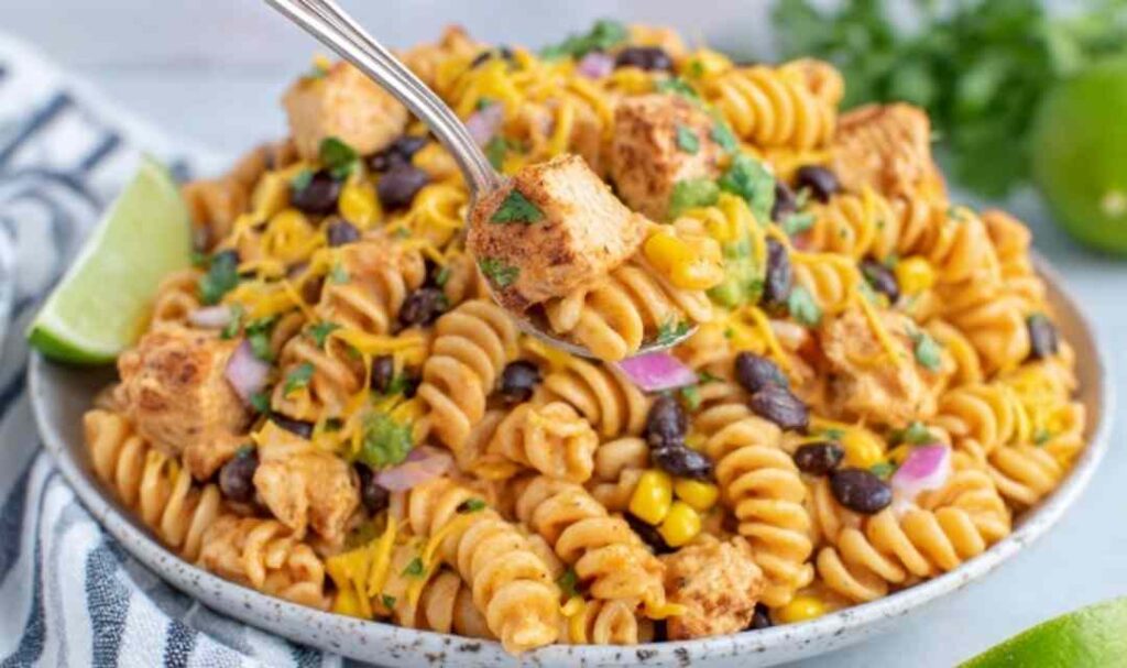 Zesty Chicken Enchilada Pasta Salad 5 Zesty Chicken Enchilada Pasta Salad in a large white bowl topped with cheddar cheese, fresh cilantro, and crushed tortilla chips