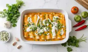 Cheesy baked buffalo chicken enchiladas in a 9x13 pan drizzled with ranch and topped with green onions