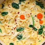 A bowl of chicken Alfredo lasagna soup topped with creamy ricotta and red pepper flakes