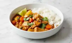 Chicken Massaman Curry (One Pot, 40 Minutes) Chicken Massaman Curry served over jasmine rice in a bowl, garnished with roasted peanuts, fresh cilantro, and a lime wedge