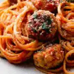 Chicken meatballs and spaghetti in a large pan with homemade tomato sauce topped with Parmesan and fresh parsley