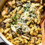 Creamy chicken mushroom pasta in a white bowl topped with fresh parsley and grated Parmesan cheese