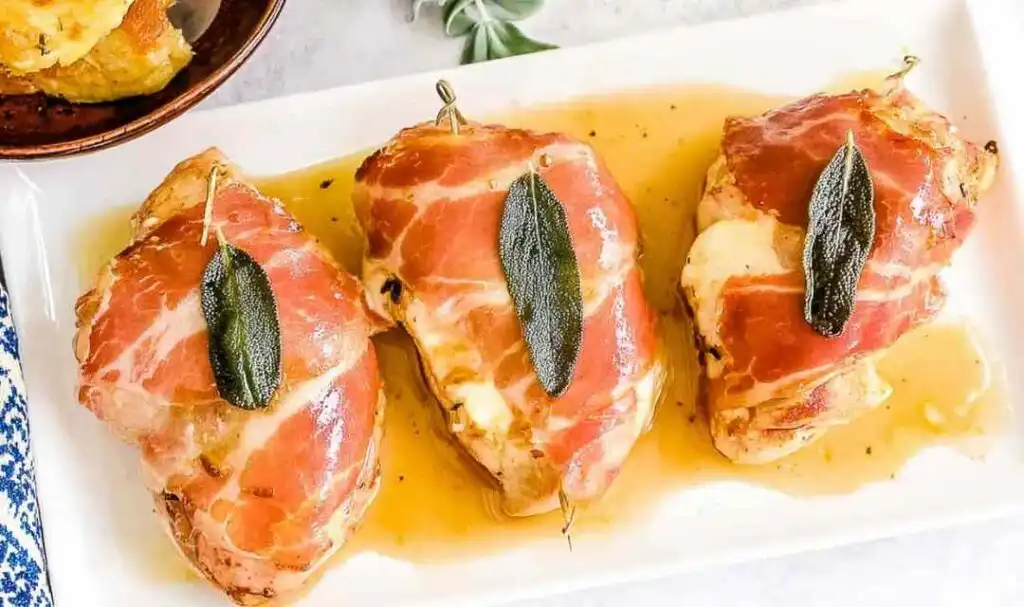 Chicken Saltimbocca with crispy prosciutto and fresh sage in white wine butter sauce on a white dinner plate
