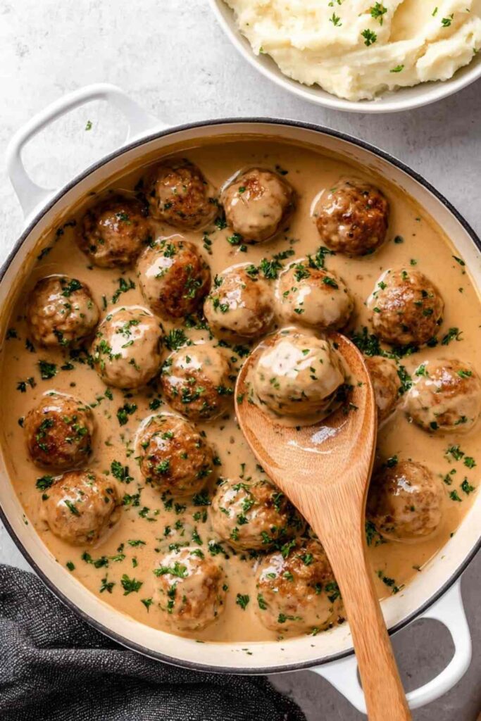 Chicken Swedish meatballs in creamy gravy served over mashed potatoes with fresh parsley garnish
