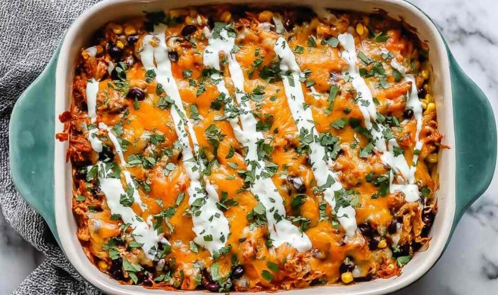 Chicken tamale casserole in a 9x13 baking dish topped with melted cheddar cheese and fresh cilantro