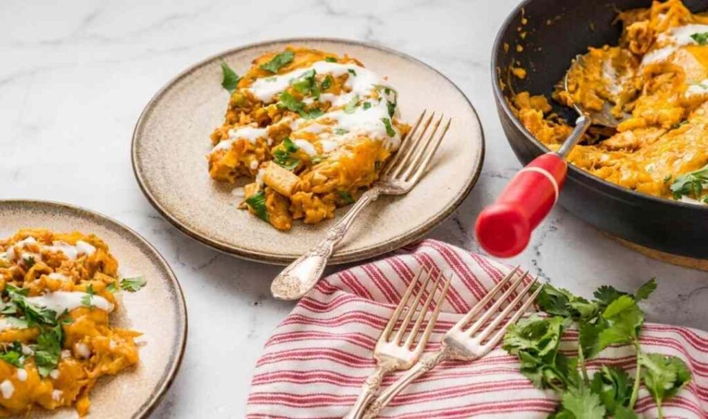 Chicken tamale pie in a cast iron skillet topped with melted Mexican cheese and fresh cilantro