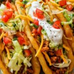 Copycat chalupas with crispy homemade shells filled with seasoned ground beef, sour cream, lettuce, tomatoes, and cheddar cheese on a wooden board