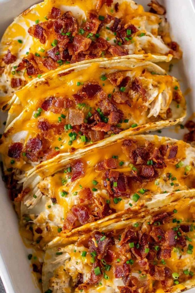 Crack chicken tacos baked in crunchy shells topped with melted cheese and crispy bacon