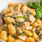 One pan creamy chicken gnocchi with sun-dried tomato pesto cream sauce and wilted spinach in a Dutch oven