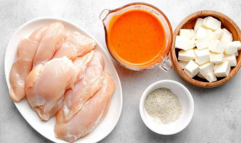 Raw chicken breasts in a crockpot coated with ranch seasoning for slow cooker buffalo chicken