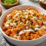 Slow cooker buffalo chicken shredded in a crockpot with buffalo sauce and butter