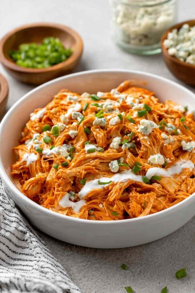 Slow cooker buffalo chicken shredded in a crockpot with buffalo sauce and butter