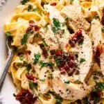 Creamy Crockpot Tuscan chicken served over fettuccine pasta with sun-dried tomatoes and Parmesan
