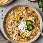 A bowl of creamy Crockpot white chicken chili topped with sliced jalapeno, fresh cilantro, and a dollop of sour cream