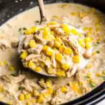 Crockpot white chicken enchilada soup recipe served in a bowl topped with avocado, sour cream, shredded cheese, and tortilla strips