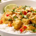 Easy chicken curry recipe served over basmati rice in a white bowl with fresh cilantro and lime wedges