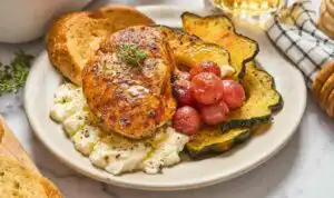 Herb roasted chicken with grapes acorn squash and ricotta served in a white ceramic baking dish with creamy ricotta dollops on top