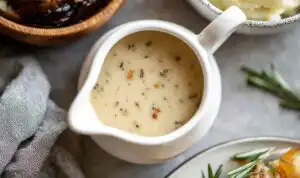 Homemade chicken gravy poured over creamy mashed potatoes in a white bowl