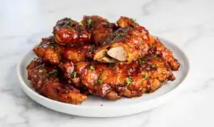 Crispy honey BBQ chicken tenders caramelized on a parchment-lined baking sheet fresh from the broiler