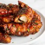 Crispy honey BBQ chicken tenders caramelized on a parchment-lined baking sheet fresh from the broiler