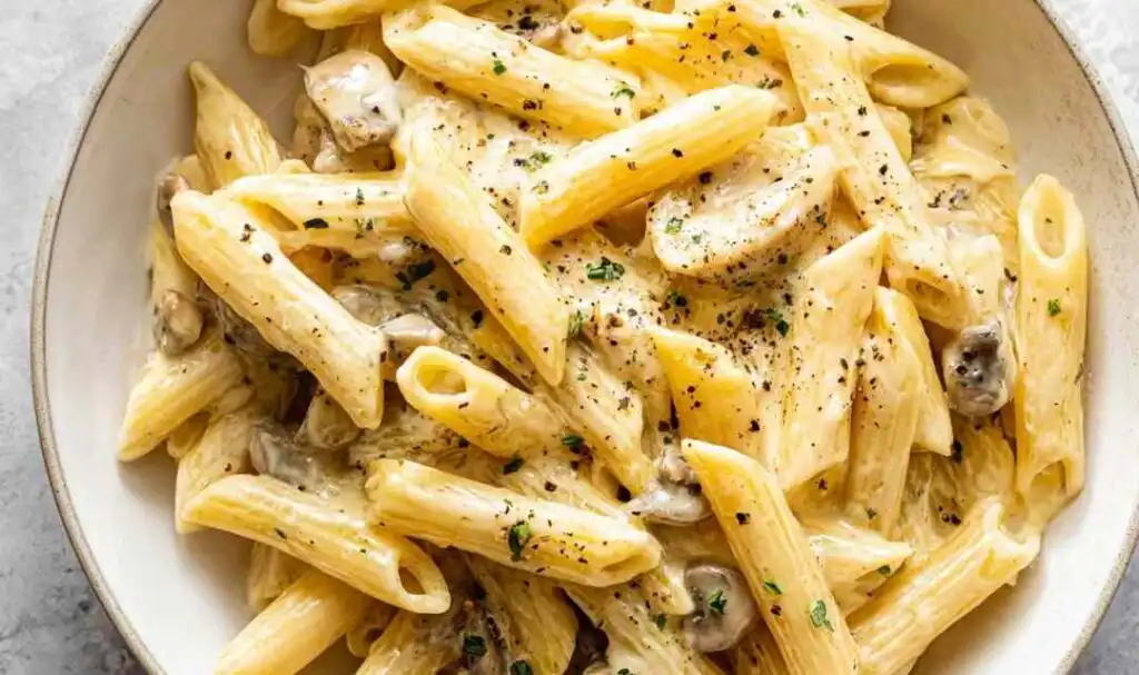 Instant Pot cheesy chicken pasta served in a white bowl topped with freshly grated cheddar and parsley