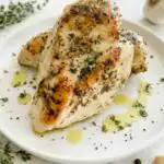 Juicy sliced Instant Pot chicken breast on a white plate garnished with fresh parsley