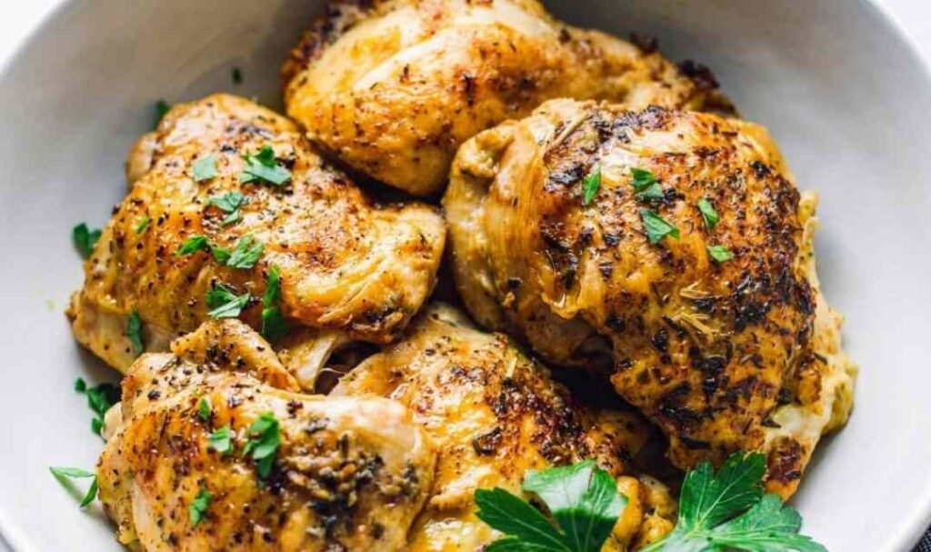 Juicy boneless Instant Pot chicken thighs sliced on a white plate with fresh parsley
