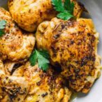 Juicy boneless Instant Pot chicken thighs sliced on a white plate with fresh parsley