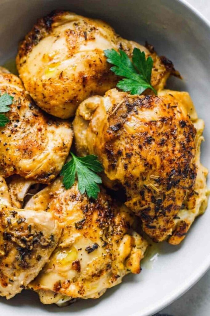 Juicy boneless Instant Pot chicken thighs sliced on a white plate with fresh parsley