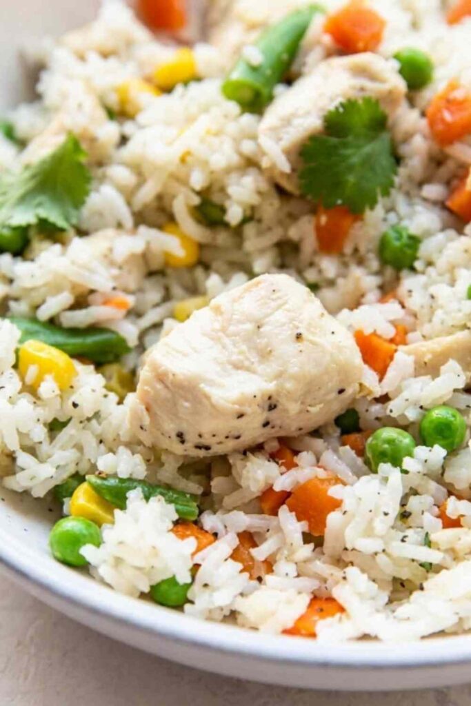 Instant Pot chicken and rice served in a white bowl topped with fresh parsley