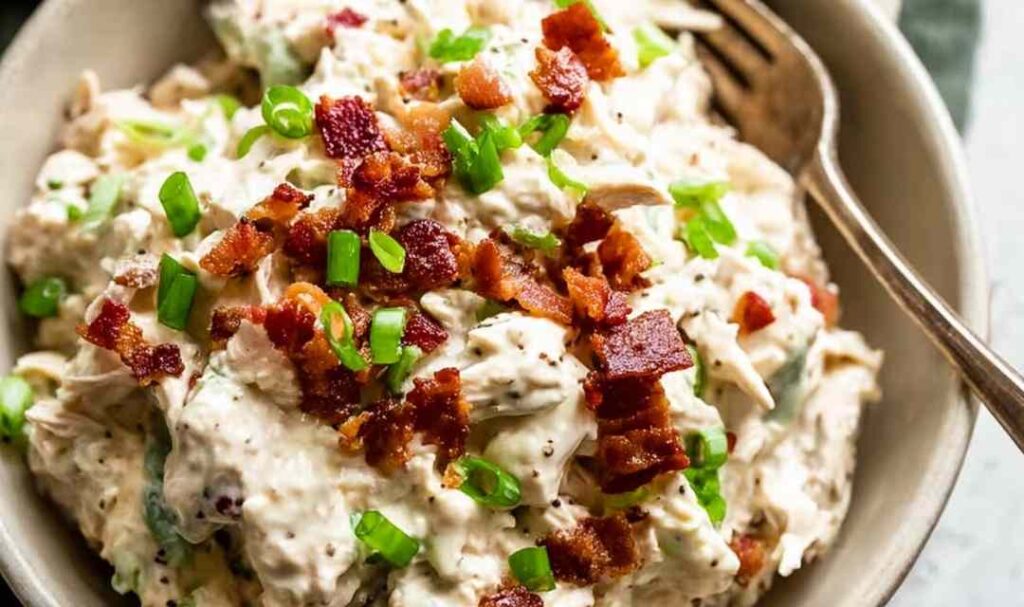Instant Pot Crack Chicken 5 Instant Pot crack chicken served over white rice in a white bowl topped with sliced green onions and crumbled bacon