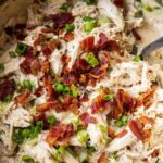 Instant Pot crack chicken served over white rice in a white bowl topped with sliced green onions and crumbled bacon