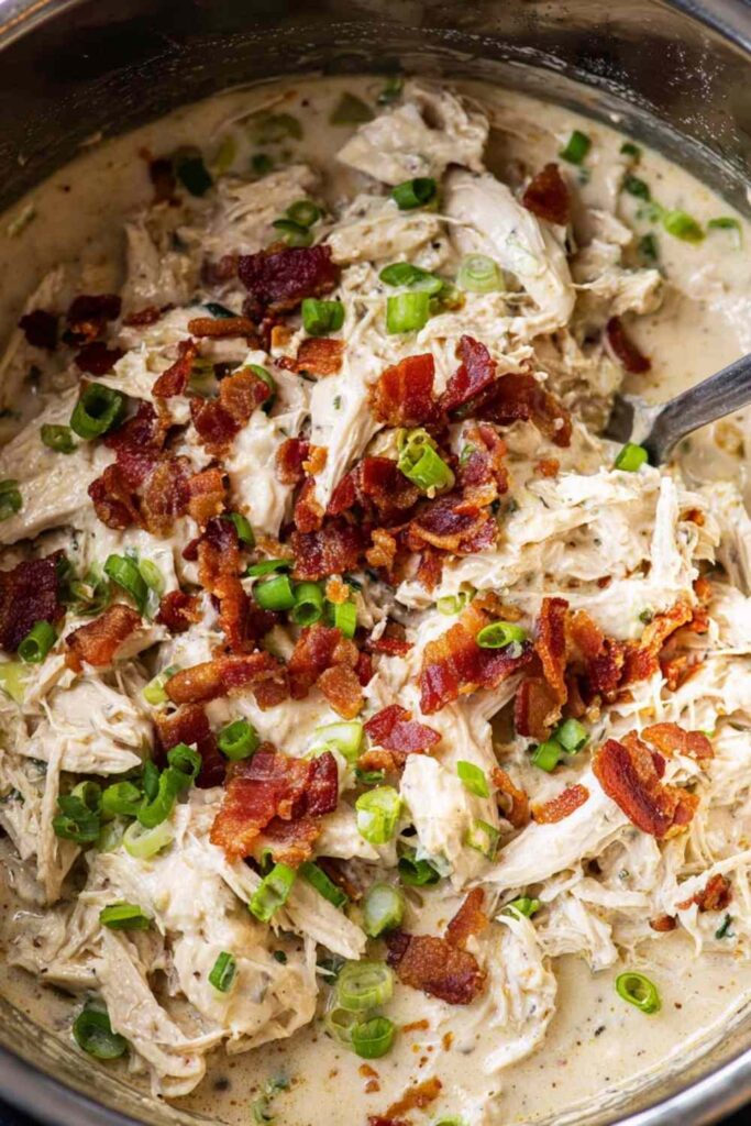 Instant Pot Crack Chicken 6 Instant Pot crack chicken served over white rice in a white bowl topped with sliced green onions and crumbled bacon
