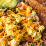 Loaded scrambled eggs with bacon, sauteed bell pepper, mushrooms, and melted cheddar in a nonstick skillet