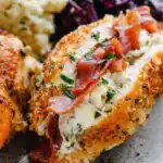 Prosciutto stuffed chicken breast sliced open to reveal creamy burrata filling on a white dinner plate