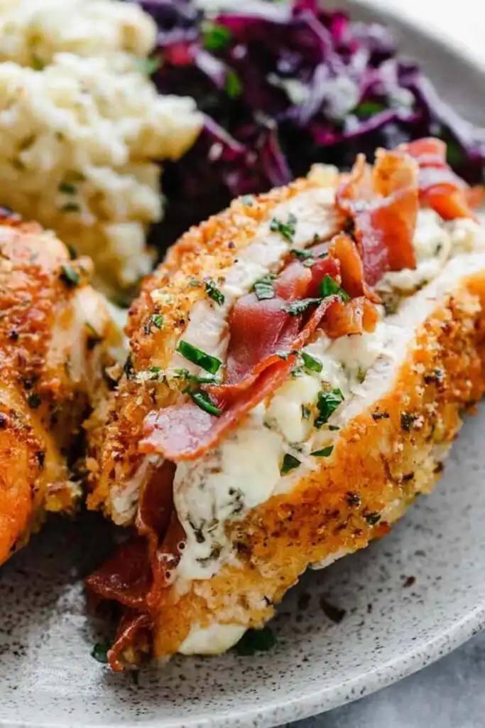 Prosciutto stuffed chicken breast sliced open to reveal creamy burrata filling on a white dinner plate