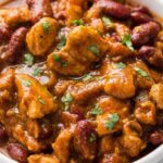 Red chicken chili recipe simmering in a Dutch oven with kidney beans and chicken breast