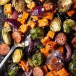 Sheet pan chicken sausage and veggies with crispy Brussels sprouts and caramelized sweet potatoes on a large baking sheet