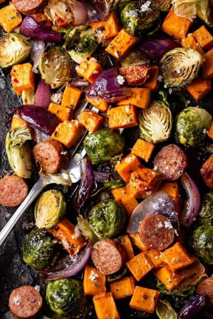 Sheet pan chicken sausage and veggies with crispy Brussels sprouts and caramelized sweet potatoes on a large baking sheet