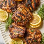 Sumac yogurt marinated chicken thighs with deep char marks served over white yogurt sauce with fresh lemon wedges